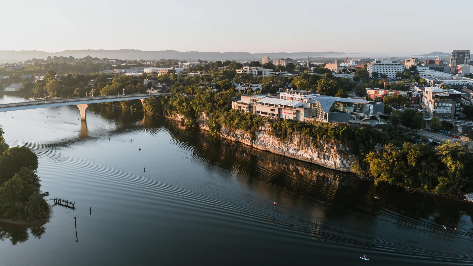 Aerial view of Chattanooga's riverfront area at sunrise showcasing modern architecture and lush greenery. in Chattanooga Scavenger Hunt