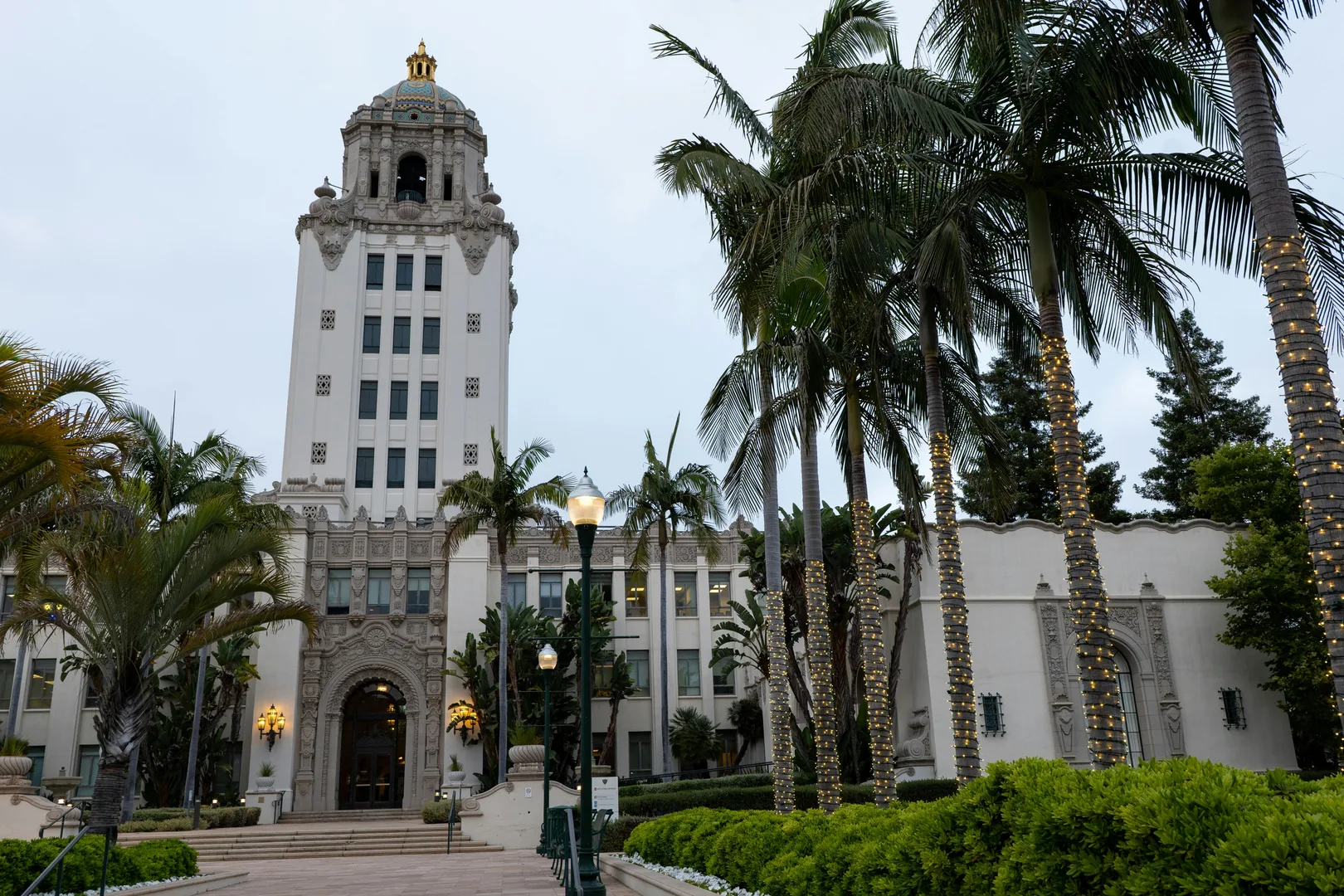 Stunning view of the iconic Beverly Hills City Hall adorned with palm trees and festive lights. in Beverly Hills Scavenger Hunt