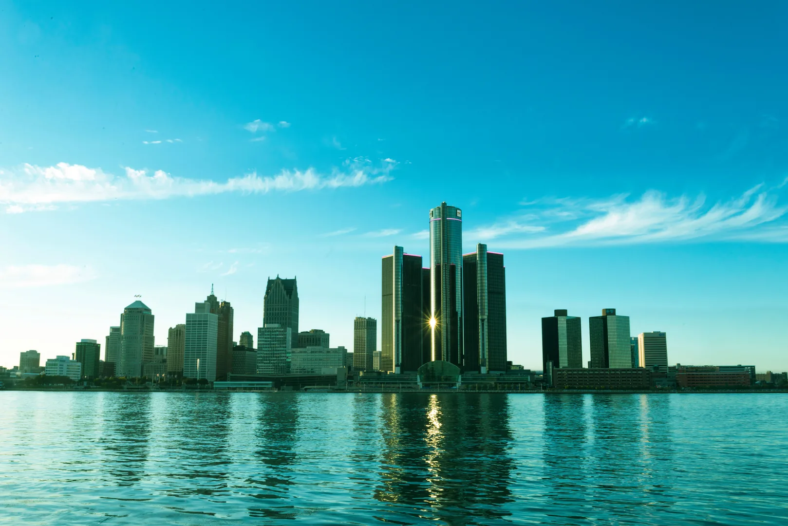 A beautiful view of the Detroit skyline reflecting on the river at sunrise, showcasing modern skyscrapers. in Detroit Scavenger Hunt